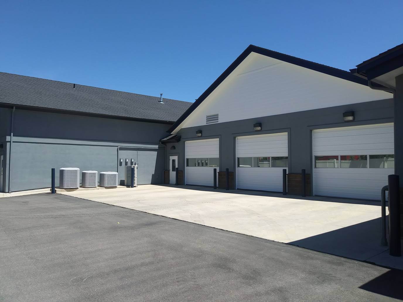 The same commercial building after exterior painting, with charcoal grey stucco, white gable siding and navy trim