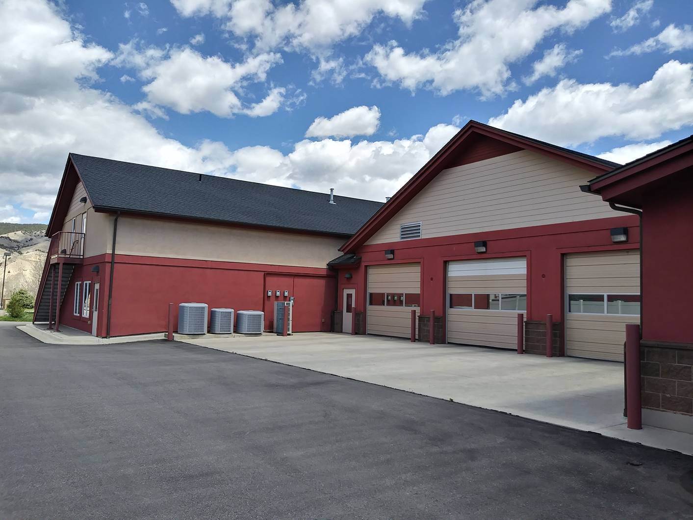 Commercial building exterior before painting, with faded barn red stucco and tan siding