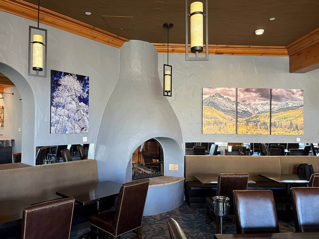 The same restaurant dining room after commercial interior painting, with light grey walls and a repainted plaster fireplace